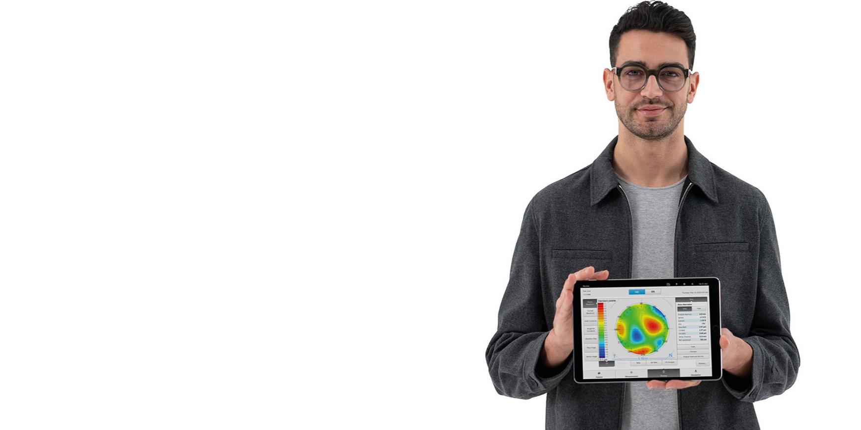 ZEISSレンズを着け、iPadを持ってカメラを見る若い男性。iPadには正確な自覚屈折検査の事前情報が表示されている。