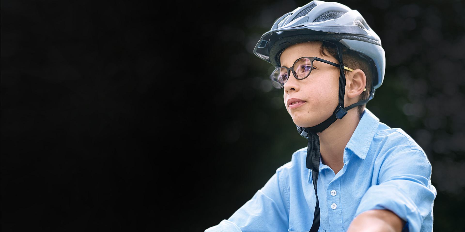 自転車に乗っているように見える、メガネとヘルメットを着けた幼い男の子。