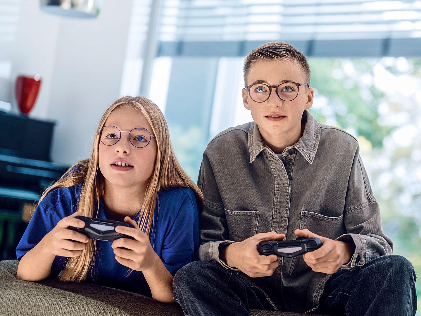 ゲーム機を持ってビデオゲームをする10代の男女。