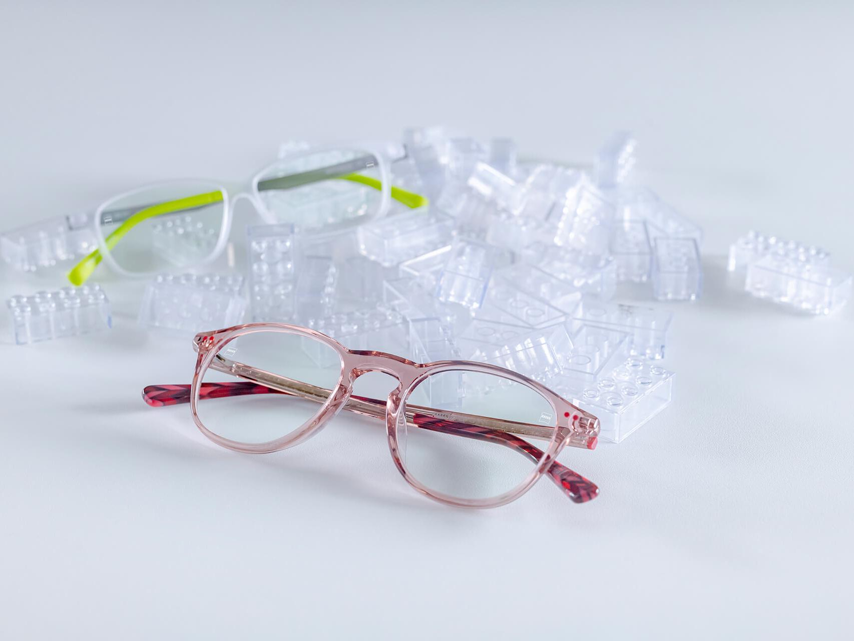 ZEISS DuraVision® キッズコーティングレンズの子ども用メガネ2本。透明な子ども用ブロックの間に置かれたメガネ。