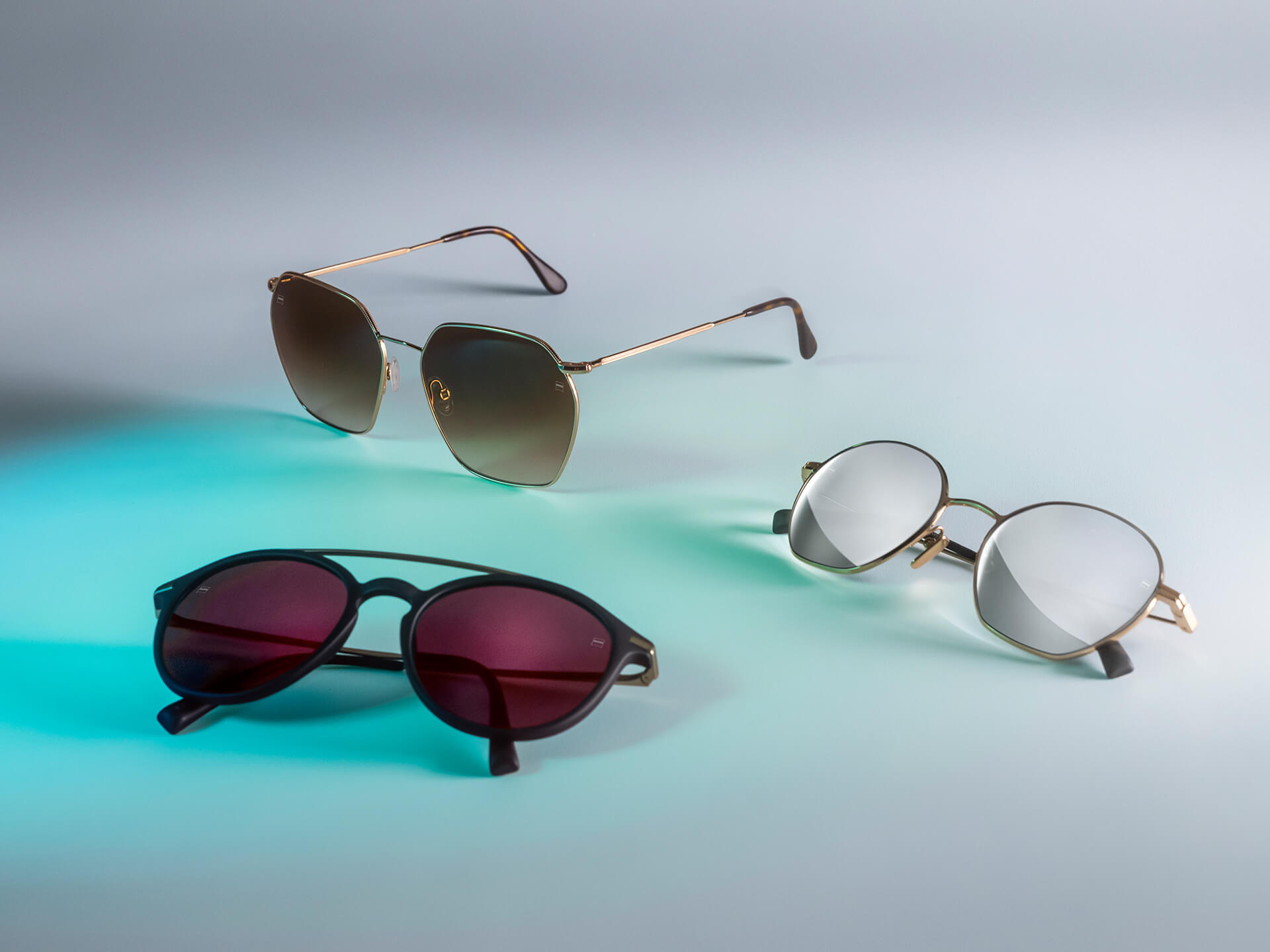 色違いのツァイス サングラスレンズの3本のサングラス。白い背景と青い反射光にDuraVision Sun、DuraVision Mirror、Flash Mirrorコーティングが見える。
