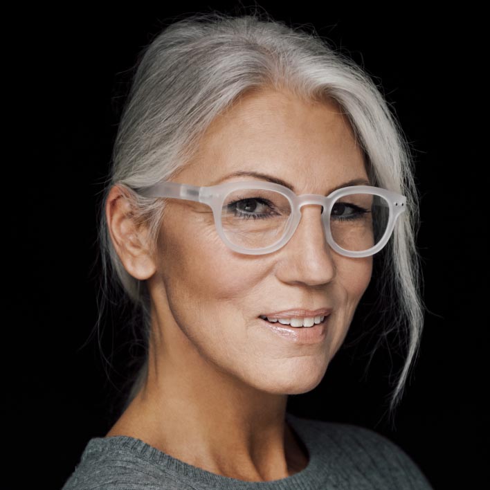 白縁フレームのZEISS SmartLife遠近両用レンズを装用した、白髪まじりの女性。顔の造りとフレームの数値を表示する、幾何学的なフェイススキャン。